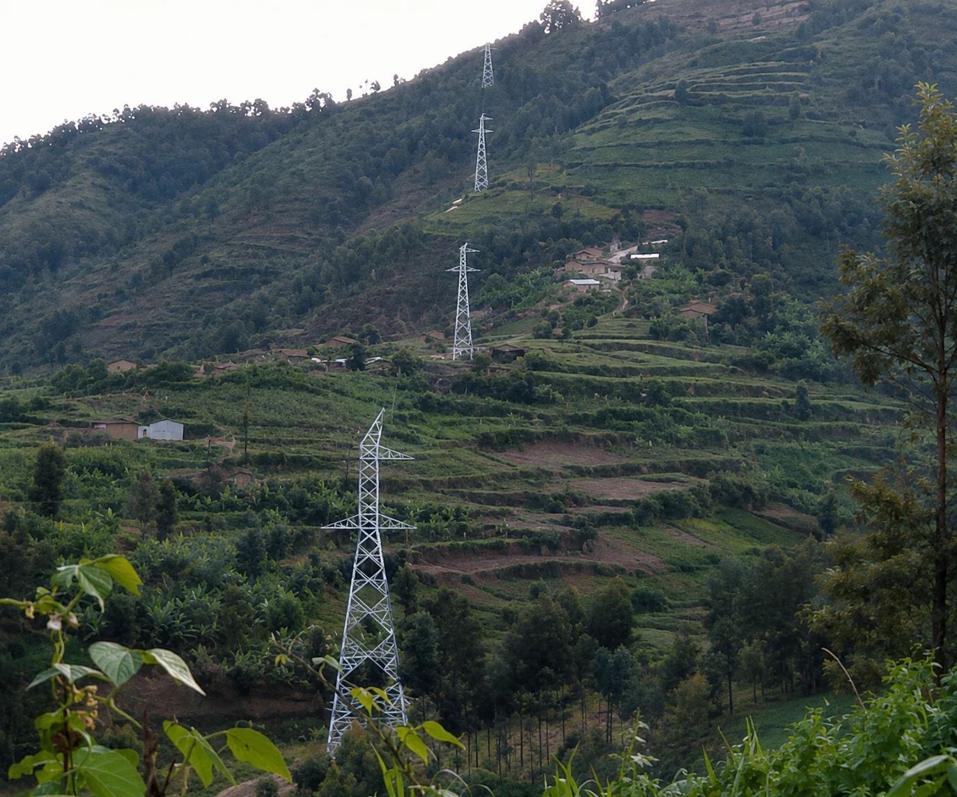 Lattice towers following a steep green mountain route in Rwanda