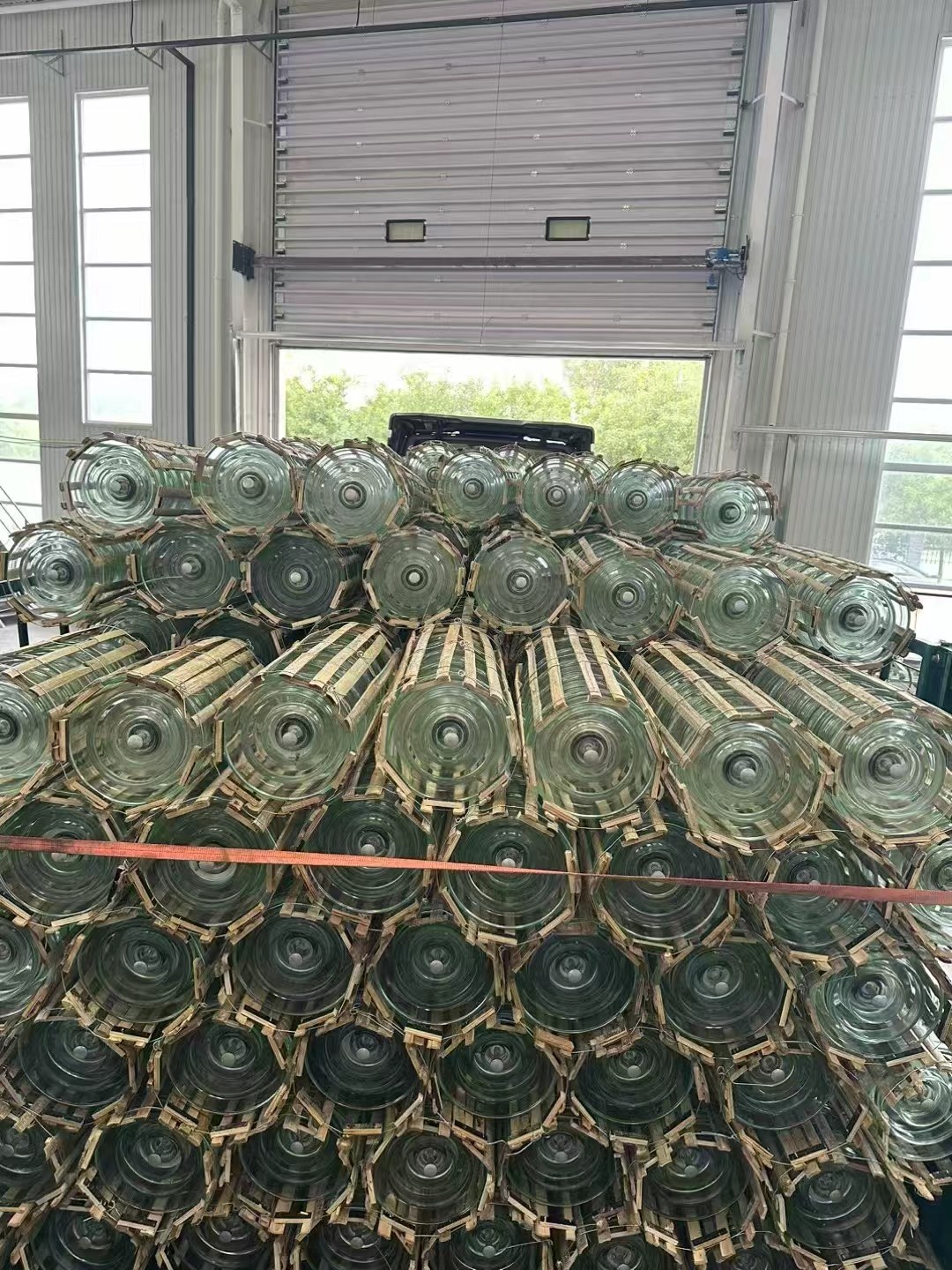 Bundled green glass disc insulator strings stacked in a warehouse